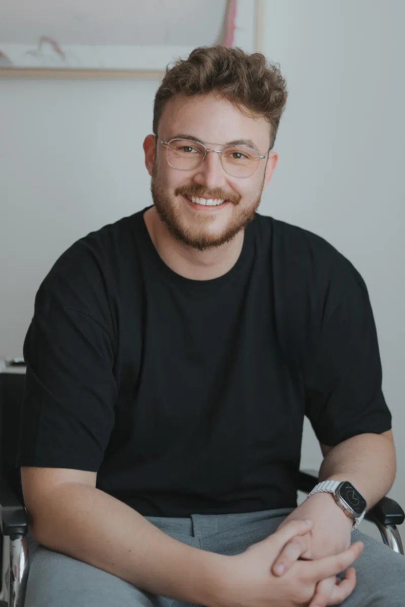 Mario Kranz von der Redaktion sitzt lächelnd mit Brille und schwarzem T-Shirt auf einem Stuhl in einem hellen Raum.
